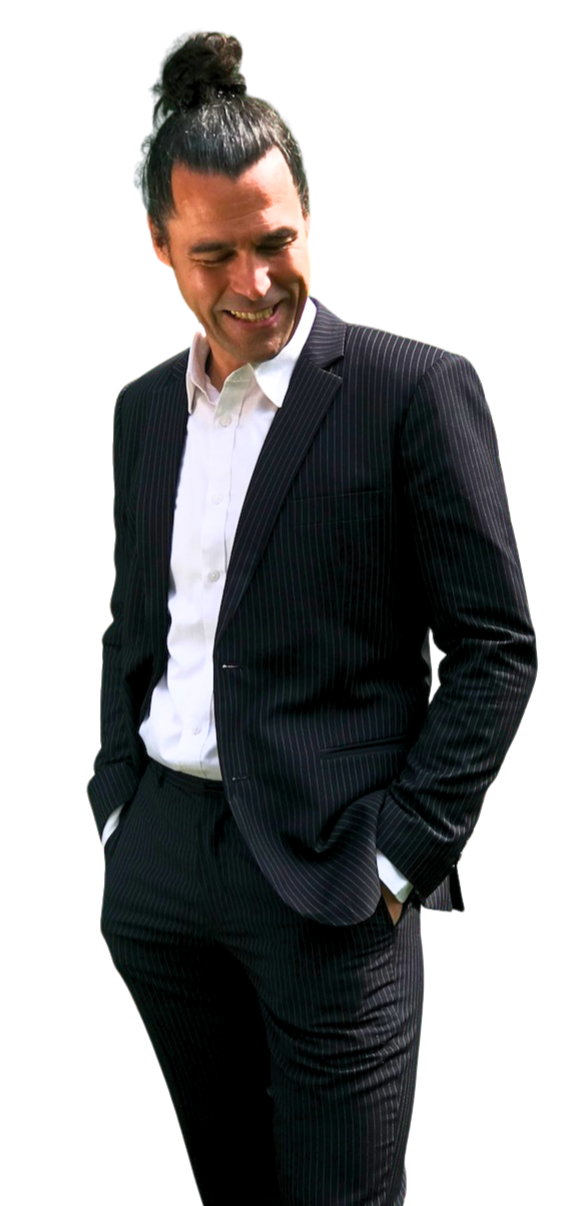 a photo of Davido, the English teacher dressed in a dark pin-striped suit and a white shirt. His hair is done up in a tight coil on the top of his head. He's holding his jacket with the right hand whilst he's smiling and looking to the right, to the area of content.